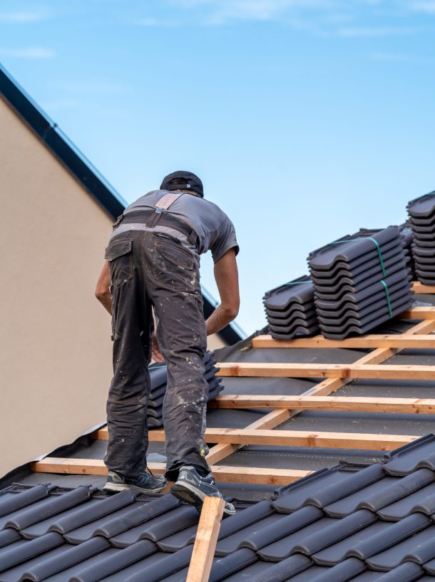 construction worker installs a fired ceramic tile on the roof.